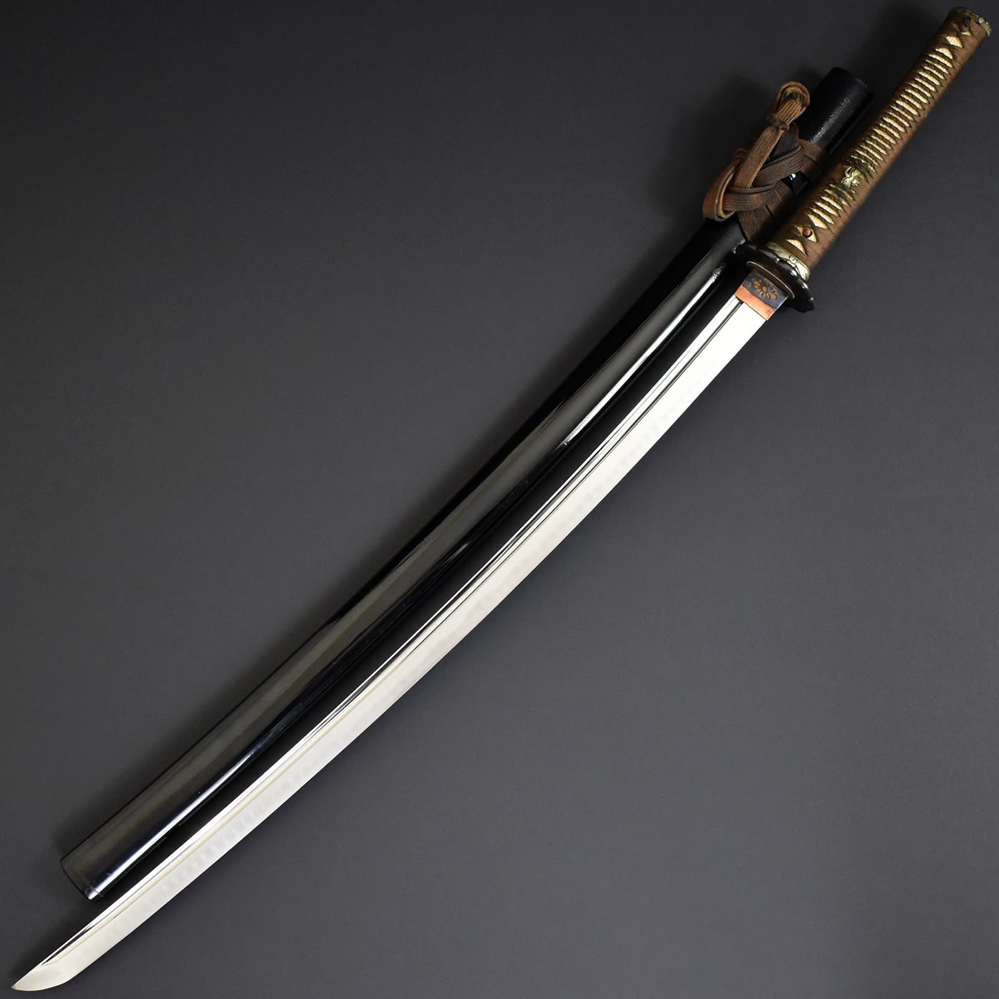 Mumei katana attributed to Yamato Daijō Masanori mounted and drawn beside its black lacquered saya