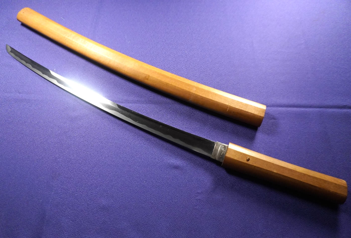 Mumei Wakizashi Study I wakizashi drawn from its plain wooden shirasaya on purple cloth