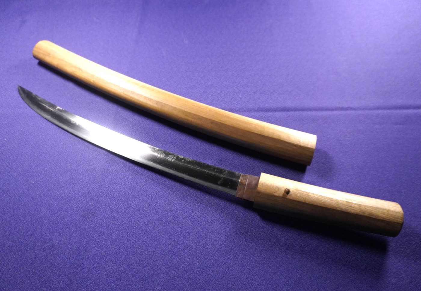 Mumei Wakizashi Study II wakizashi drawn from its plain wooden shirasaya on purple cloth