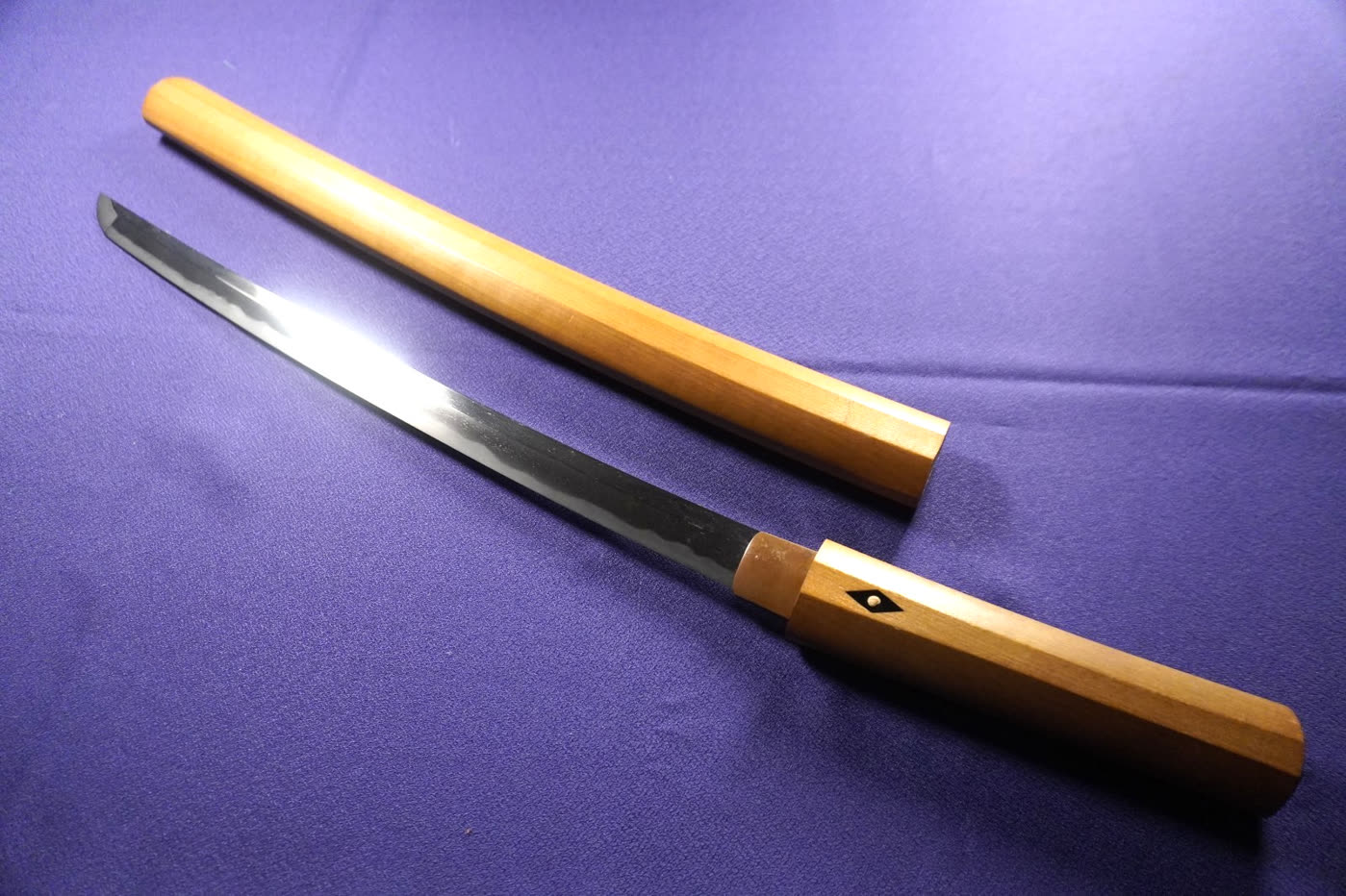 Mumei Wakizashi Study IV wakizashi drawn from its plain wooden shirasaya on purple cloth