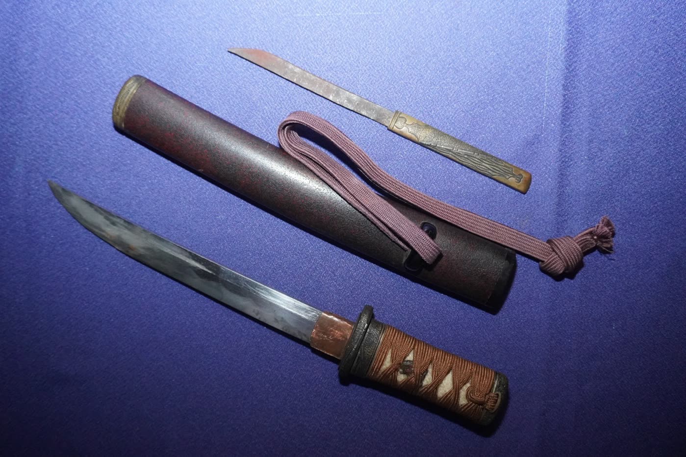 Tantō drawn beside its red-flecked lacquer saya with the kozuka and kogatana laid above